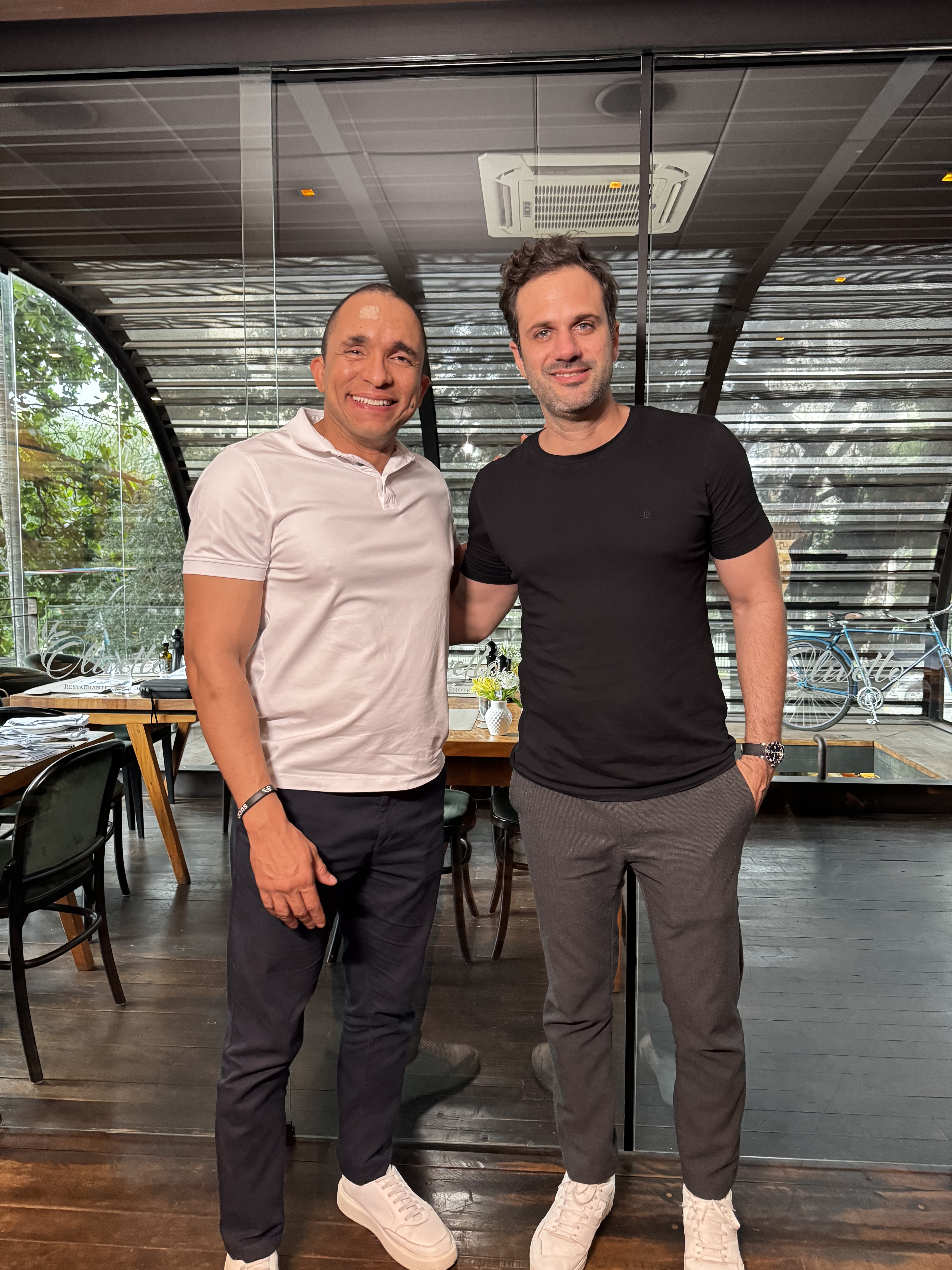 Thiago Lago em jantar com convidado em ambiente de restaurante.